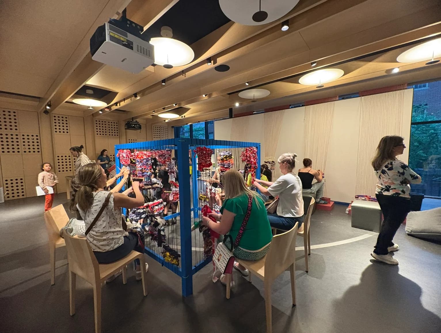 Participants weaving around a blue collaborative loom at the MoMA activation